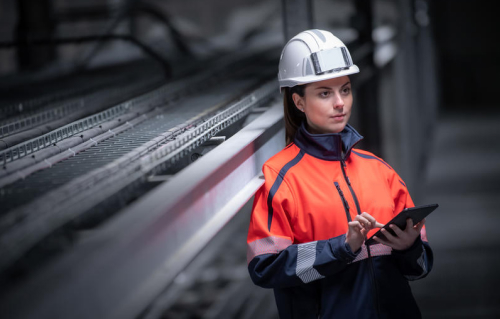 Photo d'une femme sur chantier avec veste fluorescente et casque de sécurité.